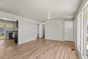 Unfurnished living room with light wood-style flooring and a textured ceiling