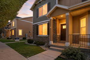 Exterior entry at dusk with stone siding, a yard, and board and batten siding