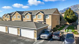 View of front of property featuring stucco siding, a shingled roof, and a residential view