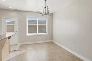 Unfurnished dining area featuring light tile patterned floors, a chandelier, and recessed lighting