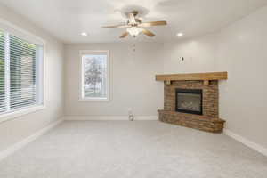 Unfurnished living room featuring light colored carpet, a stone fireplace, recessed lighting, and ceiling fan