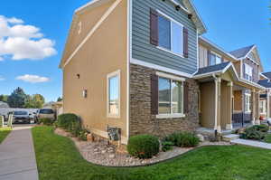 View of home's exterior featuring stone siding, a lawn, stucco siding, and covered porch