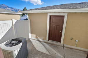Property entrance featuring stucco siding, a shingled roof, and a mountain view