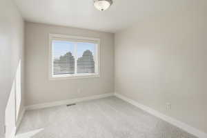 Carpeted spare room featuring baseboards