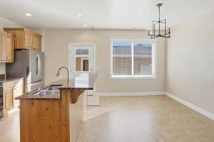 Kitchen featuring dark stone countertops, hanging light fixtures, light tile patterned floors, freestanding refrigerator, and recessed lighting