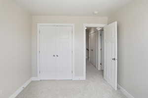Unfurnished bedroom featuring light colored carpet and a closet