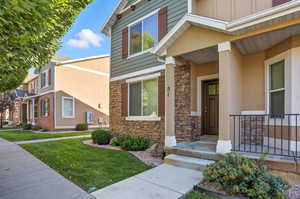 Doorway to property featuring stone siding, a lawn, board and batten siding, and covered porch