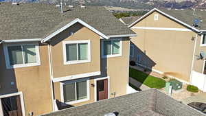 Back of property featuring roof with shingles, stucco siding, and a mountain view