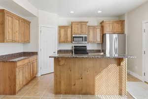 Kitchen with stainless steel appliances, light tile patterned flooring, dark stone countertops, and recessed lighting