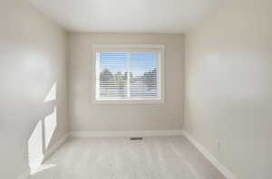 Empty room with light colored carpet and baseboards