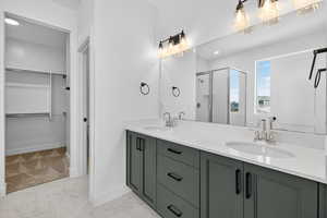 Bathroom with double vanity, a shower stall, a walk in closet, light marble finish flooring, and recessed lighting
