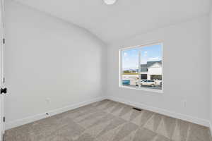 Carpeted empty room with lofted ceiling and baseboards