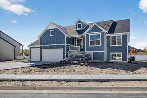 View of front of property featuring a shingled roof, driveway, board and batten siding, and covered porch