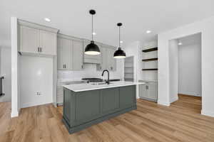 Kitchen featuring tasteful backsplash, gray cabinets, open shelves, decorative light fixtures, and recessed lighting