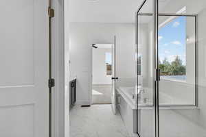 Bathroom featuring a garden tub, light marble finish floors, and vanity