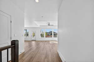 Hallway with a tray ceiling, light wood-style flooring, and recessed lighting