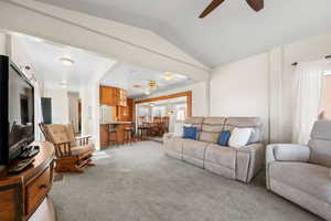 Living area with ceiling fan, light carpet, and vaulted ceiling
