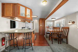 Kitchen featuring brown cabinets, a kitchen breakfast bar, light countertops, dark wood finished floors, and freestanding refrigerator