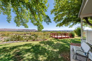 View of grassy yard featuring a deck with mountain view