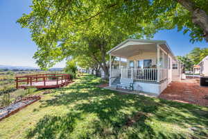 Back of house with a lawn, a deck, a ceiling fan, and a patio area
