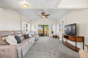 Living room with lofted ceiling, carpet flooring, and ceiling fan