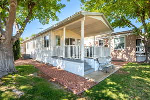 Back of house with covered porch and a lawn