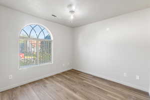 Empty room with light wood finished floors and a textured ceiling