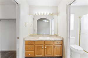 Bathroom featuring vanity, a stall shower, a walk in closet, and a ceiling fan