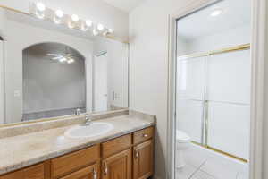 Full bath with light tile patterned floors, a shower stall, vanity, and ceiling fan