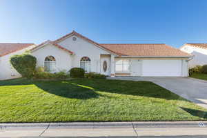 Mediterranean / spanish-style house with stucco siding, driveway, a front lawn, and a tile roof