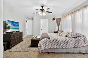Carpeted bedroom featuring a ceiling fan and a closet