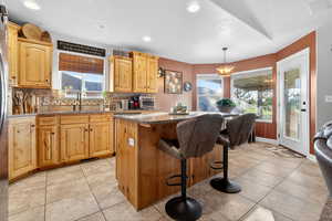 Kitchen featuring a breakfast bar area, dark stone countertops, pendant lighting, light tile patterned floors, and a kitchen island