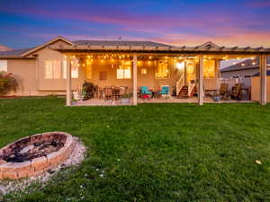Back of house featuring a patio, stucco siding, a fire pit, and a yard