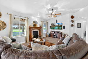 Living area with vaulted ceiling, arched walkways, carpet, plenty of natural light, and a glass covered fireplace