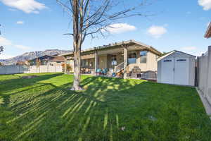 Back of house featuring a fenced backyard, a patio area, a shed, and a mountain view