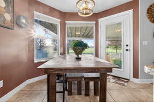 Dining room featuring plenty of natural light, light tile patterned floors, and a chandelier