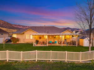 View of front of home with a patio, a storage shed, a mountain view, and roof with shingles