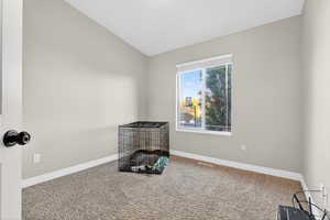 Carpeted empty room featuring baseboards and vaulted ceiling