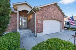 View of front facade featuring brick siding, concrete driveway, and a garage