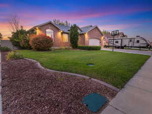 Ranch-style home featuring brick siding, a front yard, concrete driveway, and an attached garage