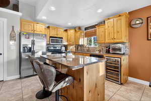 Kitchen with appliances with stainless steel finishes, light brown cabinetry, tasteful backsplash, a kitchen island, and recessed lighting