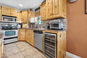 Kitchen with stainless steel appliances, light brown cabinets, and tasteful backsplash