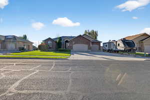 Single story home with a front lawn, driveway, an attached garage, and brick siding