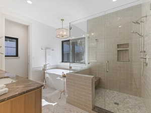 Bathroom with vanity, a soaking tub, a stall shower, recessed lighting, and tile walls