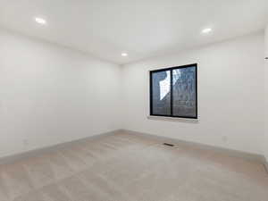 Spare room featuring light colored carpet and recessed lighting