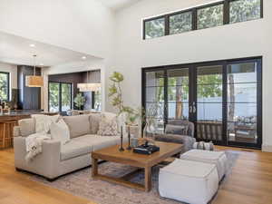 Living room featuring light wood-style floors, plenty of natural light, a high ceiling, and recessed lighting