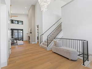Entrance foyer with light wood-style flooring, a towering ceiling, recessed lighting, stairway, and a chandelier