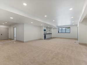 Unfurnished living room featuring light colored carpet, recessed lighting, and wine cooler