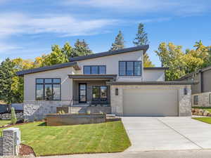 Contemporary home with stone siding, driveway, and a front yard