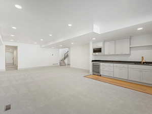 Kitchen with dark countertops, white cabinetry, open shelves, recessed lighting, and beverage cooler